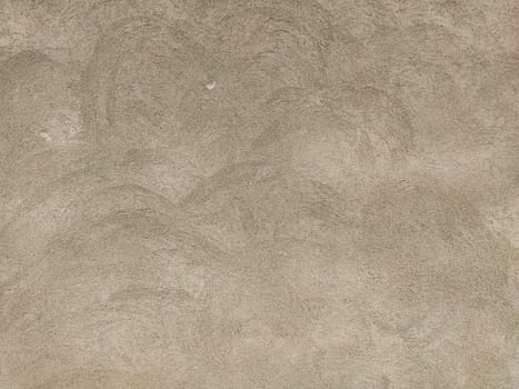Concrete surface with multi-colored blotches of small stones. Light beige tone. Wall of a building or concrete slab. Close-up. Pockmarked cement surface.