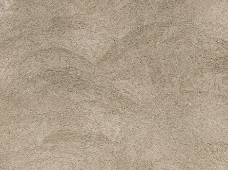 Concrete surface with multi-colored blotches of small stones. Light beige tone. Wall of a building or concrete slab. Close-up. Pockmarked cement surface. Interior or exterior finish option