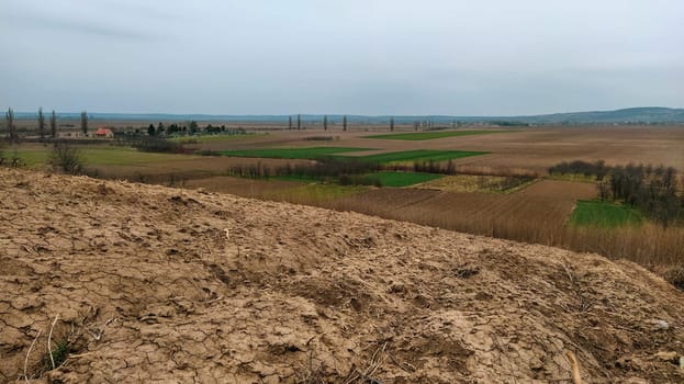 Freshly plowed field. Arable land with fertile soil for planting wheat. Rural landscape in Serbia, Balkans, namely Fruska Gora from Sremska Mitrovica. Furrows and pits. Preparatory agricultural work.