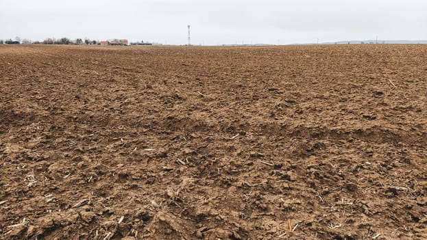 Freshly plowed field. Arable land with fertile soil for planting wheat. Rural landscape in Serbia, Balkans, namely Fruska Gora from Sremska Mitrovica. Furrows and pits. Preparatory agricultural work.