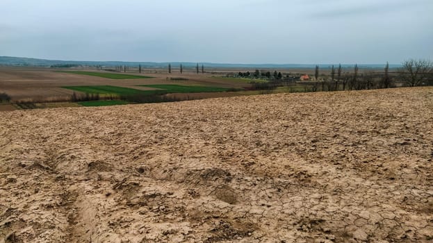 Freshly plowed field. Arable land with fertile soil for planting wheat. Rural landscape in Serbia, Balkans, namely Fruska Gora from Sremska Mitrovica. Furrows and pits. Preparatory agricultural work.