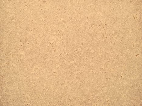 Granite is yellow-brown in color with small light and dark specks, uneven scratches. The texture of the stone. Warm colors and shades. Dim background.