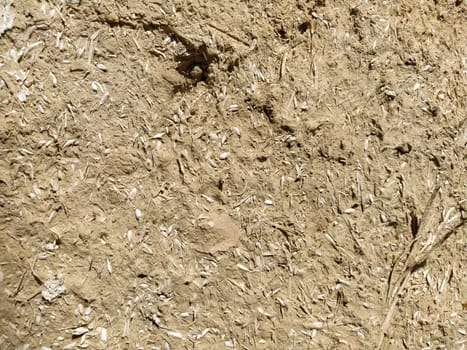 Close-up background of the wall of an old house made of clay mixed with straw. Old type of construction. Clay wall of straw and mud. Manure mixed with clay and dried as building material.