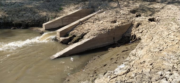 A large city drain drains sewage into a canal that flows into the river. Ecological problem. The concept of environmental protection and ecology. Concrete structure that removes contaminants into the water of the reservoir