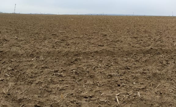 Plowed field. Arable land with fertile soil for planting crops. Rural landscape in Serbia, in the Balkans. Furrows and pits. Panorama.