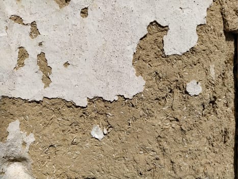 Close-up background of the wall of an old house made of clay mixed with straw. Old type of construction. Clay wall of straw and mud. Manure mixed with clay and dried as building material.