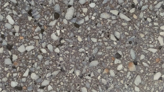 Concrete surface with multi-colored spots of small stones. The gray wall of the building, concrete slab, or granite step. Close-up. Spotty cement surface. Interior or exterior decoration.