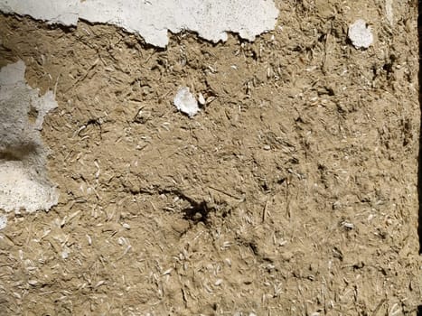 Close-up background of the wall of an old house made of clay mixed with straw. Old type of construction. Clay wall of straw and mud. Manure mixed with clay and dried as building material.