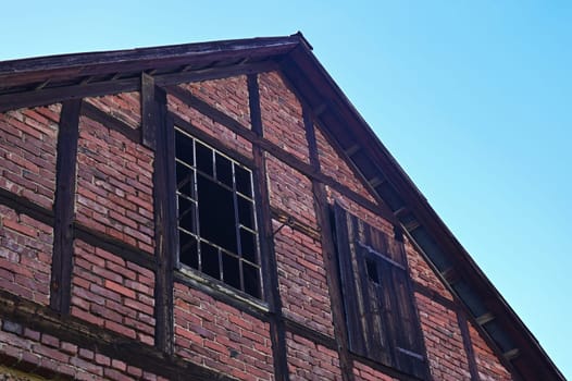 Facade of an old house with metal grille windows and broken glass panes in an old vacant building