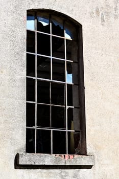 Window with metal bars and broken panes of glass in an old derelict building