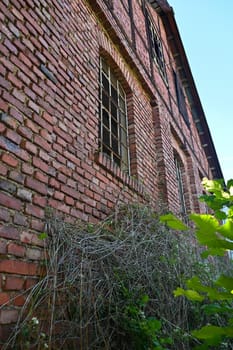 Facade of an old house with metal grille windows and broken glass panes in an old vacant building