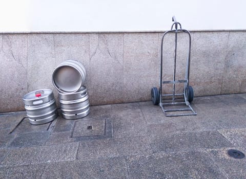 Beer kegs and trolley at downtown street. Beverage distribution concept
