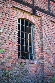 Window with metal bars and broken panes of glass in an old derelict building