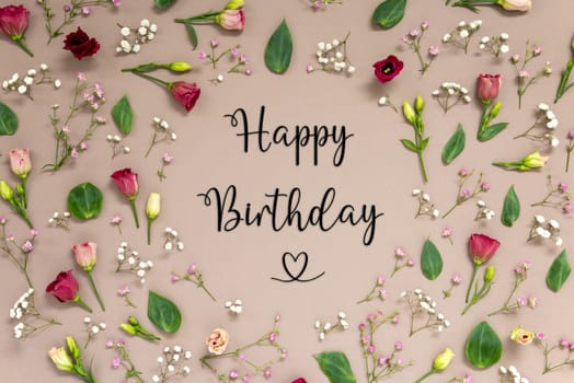 Flower Arrangement With English Text Happy Birthday. Colorful Spring Blossoms And Flowers Like Roses Building A Frame. Flat Lay With Brown Paper Background