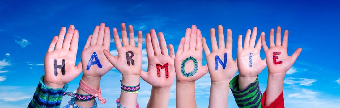 Children Hands Building Colorful German Word Harmonie Means Harmony. Blue Sky As Background