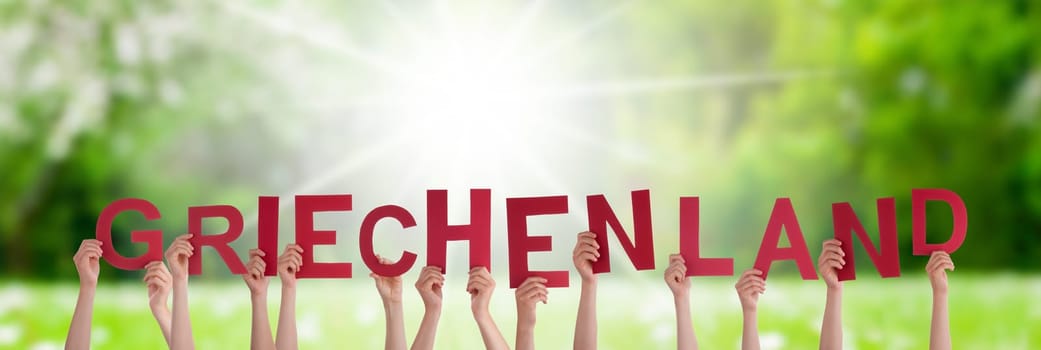 People Or Persons Hands Building German Word Griechenland Means Greece. Sunny Green Grass Meadow As Background.