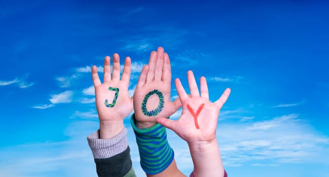 Children Hands Building Colorful English Word Joy. Blue Sky As Background