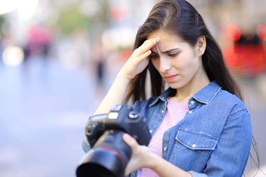 Worried photographer checking photoshoot results on camera in the street