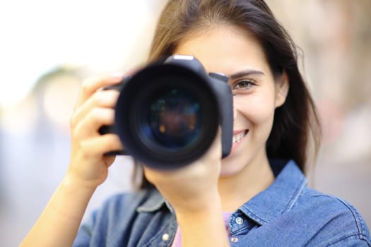Front view portrait of a happy photographer taking photo of you