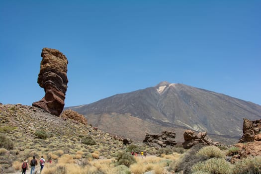 The bizarrely shaped Roque Cinchado rock of volcanic rock in Teide National Park on the Canary Island of Tenerife, Spain. With views of Mount Teide and blue skies.