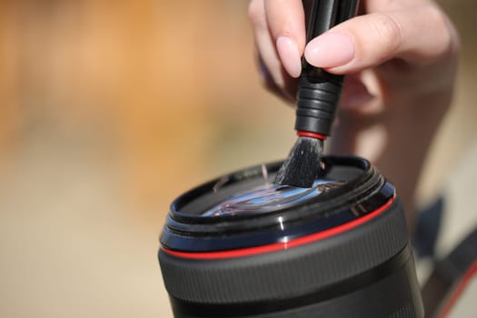 Close up of a photographer hand cleaning lens outside in a park