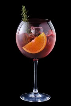 Cold sangria with orange and rosemary in a wine glass isolated on black background