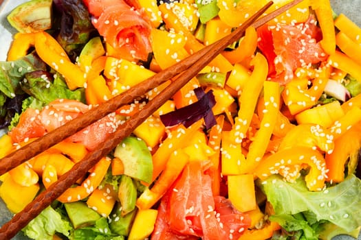 Asian salad with smoked salmon, mango, sesame and vegetables. Close up.