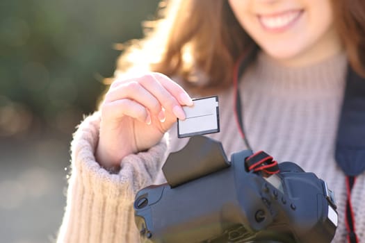 Close up of a photographer inserting card on dslr camera in winter