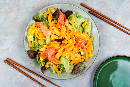 Asian salad with smoked salmon, mango, sesame and vegetables. Close up.