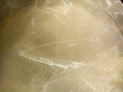 Organza in white and beige or champagne color close-up. Lightweight sheer tulle curtains under side lighting.
