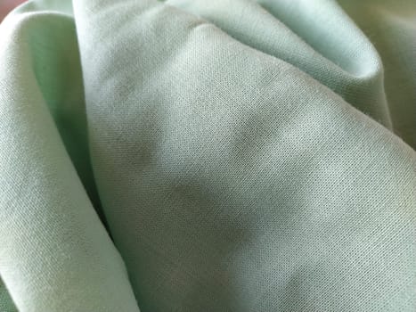 Close up of a woolen fabric of green color. Abstract canvas background, empty template. Thin natural fabric, wool or linen.