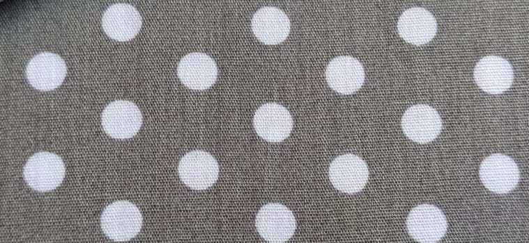 fabric white polka dots on a gray background, smoothed flat surface.