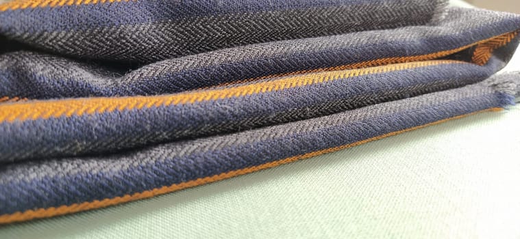 Light green and black-gray folded fabric with orange and dark blue stripes. Interior decoration. Dress fabrics in casual style. Dense material for indoor curtains and furniture finishing.