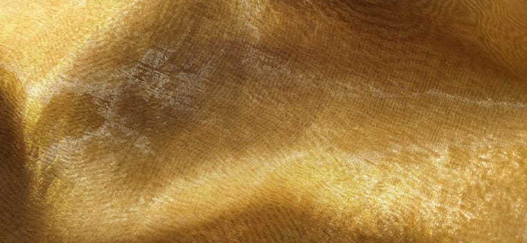 Beautiful gold fabric. Organza in yellow, orange, beige and brown shades. Pleats in the fabric. Shiny gradient under the light. Folded silky tulle. Transparent curtain material.