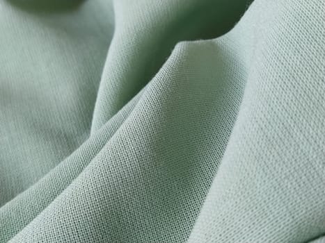Close up of a woolen fabric of green color. Abstract canvas background, empty template. Thin natural fabric, wool or linen.