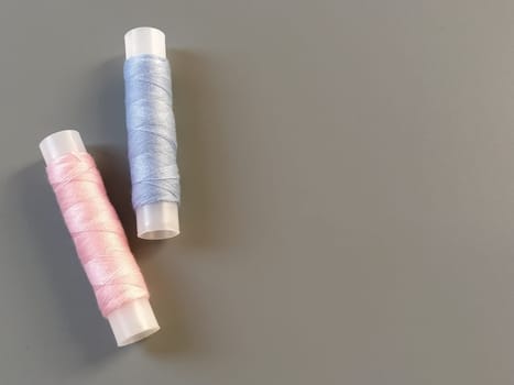 Spools of pink and blue thread on a gray background. Textile industry.
