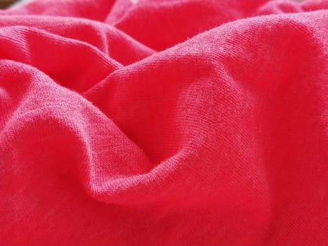 Bright pink or magenta polyester fabric, wrinkled or folded carelessly. Saturated background. Defocused photo around the edges of the photo