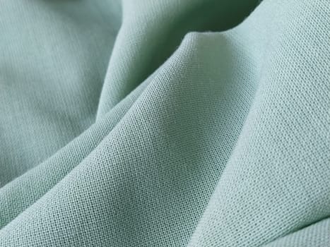 Close up of a woolen fabric of green color. Abstract canvas background, empty template. Thin natural fabric, wool or linen.