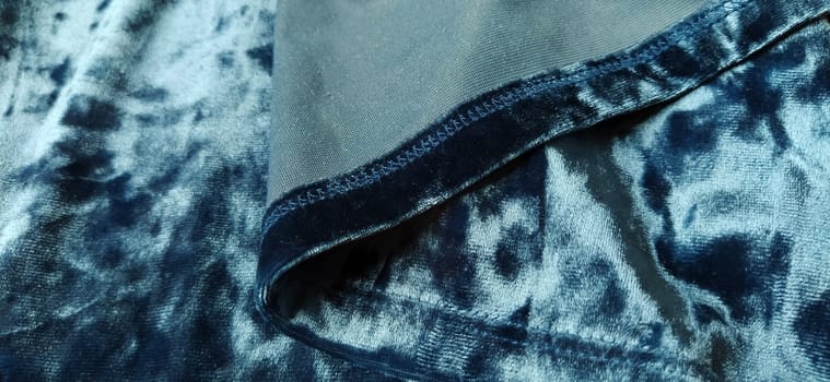 Velvet velor cloth background with glowing light and dark shadows. Background for theater and fashion design themes. Nice blue fabric with overflow.