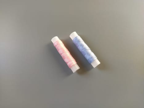 Spools of pink and blue thread on a gray background. Textile industry.