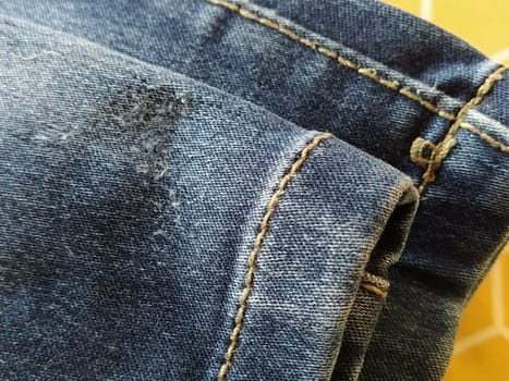 Denim fabric with seams made with red or beige threads close-up. Textile texture. Blue color of the material. Light industry sewing product. Fashion elements on jeans.
