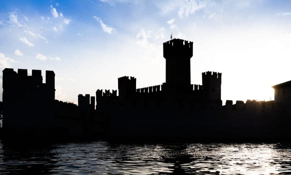 Italy - Sirmone castle silhouette on the Garda lake at sunset. Medieval architecture with tower