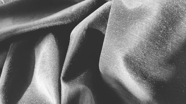 black fabric with interlacing threads close-up. Black and white monochrome photography. Nice beautiful waves on the material. Folded fabric. Interior decoration, sewing clothes and curtains. Textile