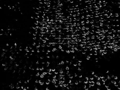 Abstract blurred background with black sequins. Gray and white elements on black.
