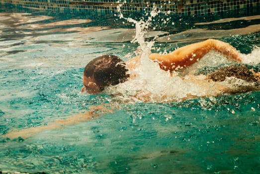 Young man swimmer train swimming in swimming pool. Recreation outdoor water sport. Vintage and retro image.