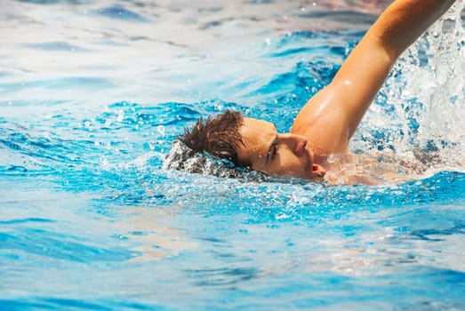 Young man swimmer train swimming in swimming pool. Recreation outdoor water sport.