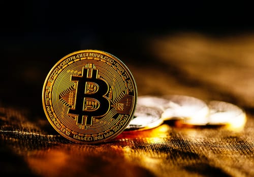 Closeup of golden bitcoin BTC cryptocurrency over black and gold background. Virtual money and blockchain concept.