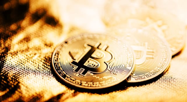 Closeup of golden bitcoin BTC cryptocurrency over gold background. Virtual money and blockchain concept.