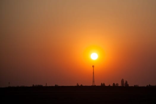 Red sunset over the field. Beautiful sunset in nature. Rural nature at sunset. Red sunset landscape