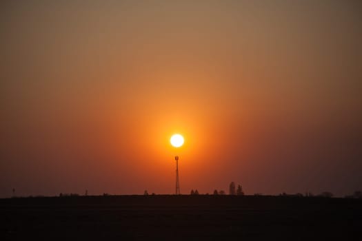 Red sunset over the field. Beautiful sunset in nature. Rural nature at sunset. Red sunset landscape